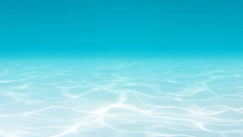 Underwater view of a soft blue gradient fading into a rippled sandy seafloor