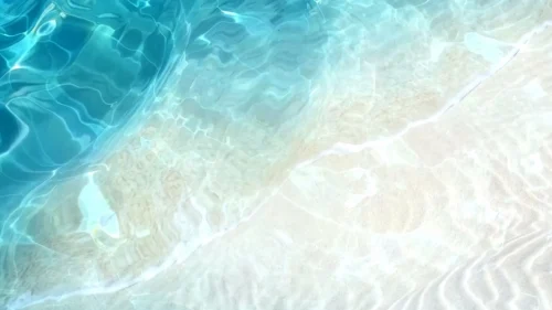 Pool water background with a deep navy blue corner cutting a diagonal into sun-dappled pale sand