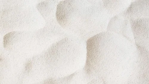 Sand background for PowerPoint with a close-up white sand grain texture and soft tan shadow patches